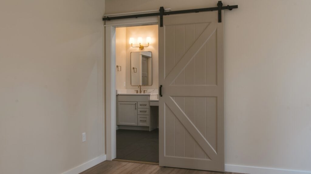 Alpenglow Builders LLC - A high-end custom home interior featuring a sliding barn door leading to a modern bathroom in Palmer and Wasilla, Alaska.