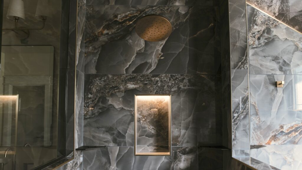 Alpenglow Builders LLC - Luxurious modern bathroom with dark marble walls, walk-in shower, and elegant lighting accents, built by Alpenglow Builders i.