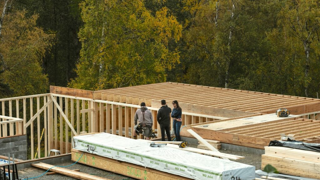 Alpenglow Builders LLC - A high-end custom luxury home under construction in Palmer, Alaska, showcasing wooden framing and scenic forest background.