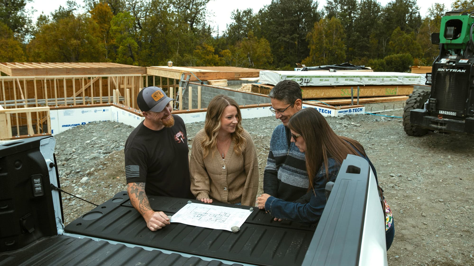 Alpenglow Builders LLC - Alpenglow Builders LLC luxury home construction site in Palmer, Alaska, with team reviewing plans outdoors.