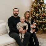 Alaska Realtor Ariel Boehringer and her family of four sitting on a white sofa in front of a decorated Christmas tree.